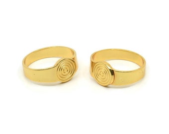 May include: Two gold rings with a spiral design on the top. The rings are simple and elegant.