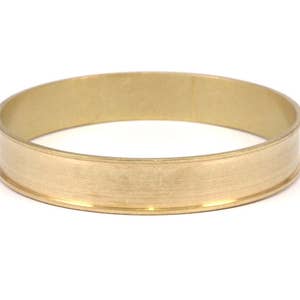 May include: A gold-colored metal ring with a wide band and a smooth, polished finish.