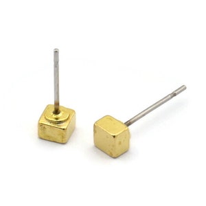 May include: A pair of gold square stud earrings with silver posts. The earrings are small and simple, making them a versatile accessory.