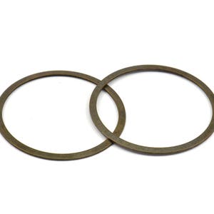 May include: Two antique gold-colored metal rings, each with a circular shape, are intertwined.