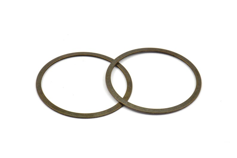 May include: Two antique gold-colored metal rings, each with a circular shape, are intertwined.