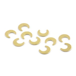 Op de afbeelding: Een verzameling van tien gouden halve maan bedels. De bedels liggen verspreid op een wit oppervlak.