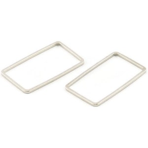 Puede incluir: Dos aros rectangulares de plata, cada uno con un borde liso y redondeado.