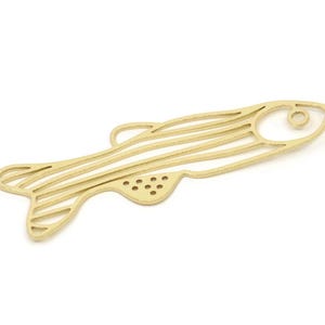 May include: Gold-colored metal fish charm with a striped pattern and a hole for attaching to a necklace or bracelet.