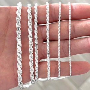 May include: A set of six silver rope chains of varying thicknesses, displayed on a hand.