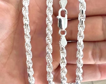 May include: A silver rope chain necklace with a lobster clasp. The chain is made of multiple strands of silver wire twisted together to form a rope-like design.
