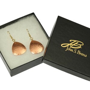 May include: A pair of copper earrings with a hammered finish, in a black gift box with gold lettering that reads "John S. Brana".