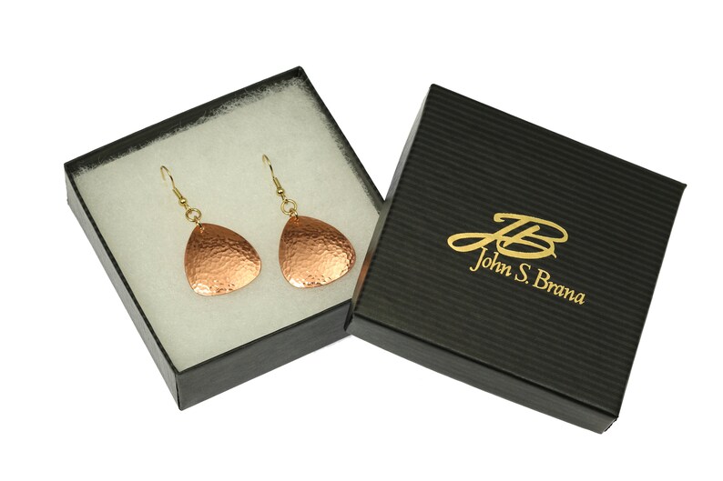 May include: A pair of copper earrings with a hammered finish, in a black gift box with gold lettering that reads "John S. Brana".