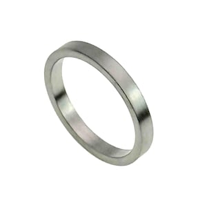 May include: A silver-colored ring with a flat band. The ring has a simple, minimalist design and appears to be made of metal. The ring is shown against a white background.