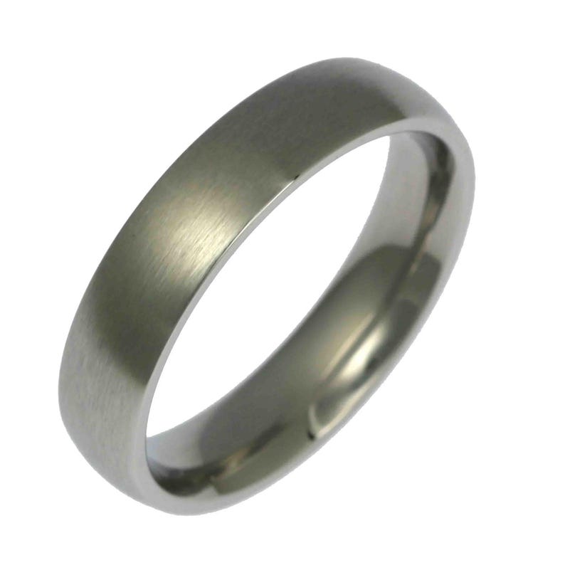 Angled close-up product image of a 5mm brushed stainless steel band ring against a plain white background. The ring features a matte brushed exterior with a soft silver tone and fine linear texture. Its edges are smoothly rounded, and the interior is polished and slightly domed for a comfort fit. Minimalist, unisex wedding band with a clean, modern design and sleek, timeless profile.
