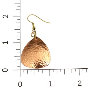 May include: A pair of hammered copper earrings with a teardrop shape and gold-tone hooks. The earrings are approximately 1 inch in length.