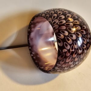 May include: A purple and white bangle bracelet with a pattern of white ovals on a purple background.