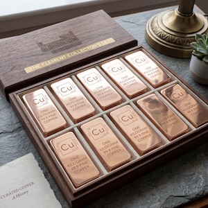 May include: A wooden box set labeled "THE ELEMENT COLLECTOR'S SET" contains ten copper bars. Each bar is stamped with "Cu", "ONE KILOGRAM 99.9 FINE COPPER". The set includes a small booklet titled "CURATED COPPER: A History".