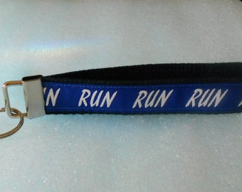 Könnte beinhalten: Blau-schwarzer Schlüsselanhänger mit einem silbernen Schlüsselring. Der blaue Riemen hat die Aufschrift "RUN RUN RUN" in weiß.