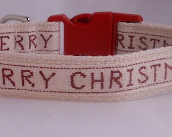 May include: A white cotton dog collar with a red plastic buckle. The collar has the words "Merry Christmas" embroidered in red thread.