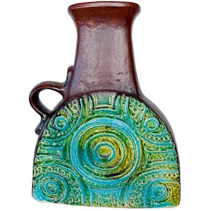 Könnte beinhalten: Eine braune Keramikvase mit Henkel, mit einem strukturierten Design in Grün- und Blautönen. Die Vase hat einen abgerundeten Boden und einen schmalen Hals, mit einer dunkelbraunen Glasur auf dem oberen Teil.