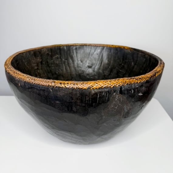 A 14.5" ebonized African mortar bowl with a woven rim — the kind of sculptural, tactile object that anchors a room and sparks a story about where it came from.