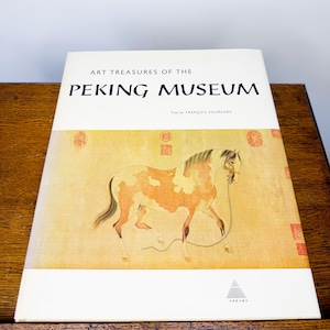 Puede incluir: Un libro titulado "ART TREASURES OF THE PEKING MUSEUM" con una pintura de un caballo. La portada es blanca con texto negro y un fondo beige. El caballo es marrón y blanco con una brida.