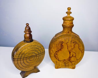 Könnte beinhalten: Zwei dekorative Holzflaschen. Eine ist rund mit einem Spiralmuster und einem kleinen Ständer. Die andere ist oval mit einem Birnenmuster. Beide haben eine hellbraune Farbe und sind aus Holz.