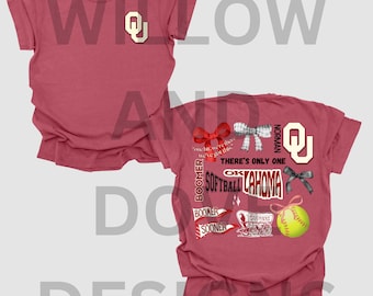 May include: A red t-shirt with a white and black graphic design featuring the text "Boomer", "There's Only One", "Softball Oklahoma", "Norman", and "Sooners". The graphic also includes a softball, a bow, and a wagon.