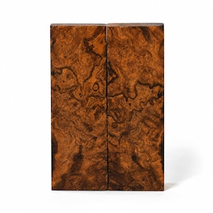 May include: Two rectangular blocks of wood featuring a dense, swirling burl grain pattern in shades of deep brown, amber, and black. The surfaces are smooth and display a complex, organic texture with dark, intricate knots and flowing lines.