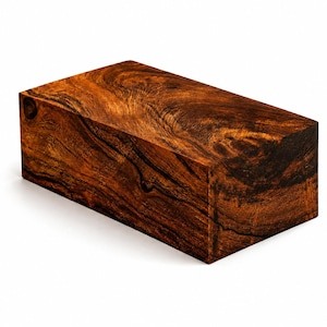 May include: A rectangular block of dark brown wood featuring a prominent, swirling grain pattern with deep black streaks and lighter amber highlights. The surface is smooth and polished, showcasing the natural texture and organic lines of the timber.