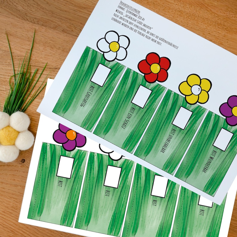 May include: Two white paper sheets featuring a green grass pattern, white rectangular boxes, and colorful flower illustrations. The text includes "BIST GROSSARTIG," "BIST EIN SCHATZ," "BIST UNBEZAHLBAR," "BIST WUNDERBAR," and "BIST" repeated four times.