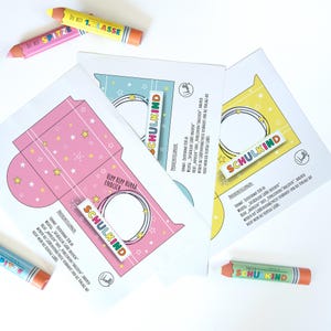 May include: A collection of school-themed stationery items. The image features three colorful paper cutouts with star and circle designs, and the word "SCHULKIND". Also included are three pencil-shaped crayons with text, including "DU BIST 1.KLASSE".