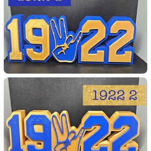 May include: Two blue and gold 3D number 1922 signs with a gold hand sign in the middle. The top sign has the number 1 in gold on a blue background and the bottom sign has the number 2 in gold on a blue background. Both signs have the text "1922" in gold on a blue background.