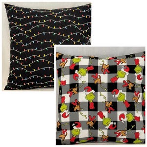 May include: Two square throw pillows. One pillow features a black background with a repeating pattern of thin, wavy white lines and small, multi-colored Christmas light bulbs. The other pillow has a black, white, and gray buffalo plaid pattern.