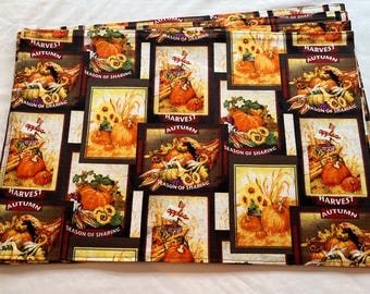 May include: A stack of autumn-themed fabric. The fabric features repeating rectangular designs with pumpkins, sunflowers, and the words "Harvest Autumn" and "Season of Sharing". The color palette includes orange, brown, and cream.
