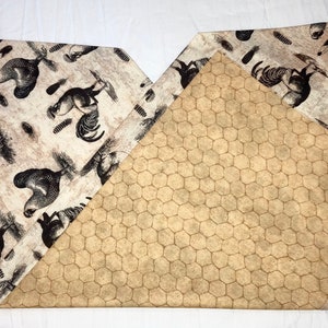 May include: A reversible table runner with a beige background. One side features a repeating pattern of black chickens and roosters. The other side features a beige honeycomb pattern.