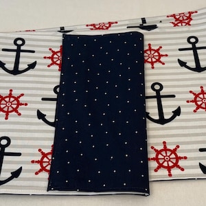 May include: Nautical-themed fabric with a white and gray striped pattern. The fabric features black anchors and red ship wheels. A navy blue fabric with white polka dots is also included.