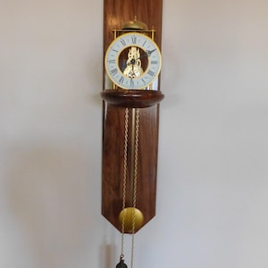 Handcrafted Satin Walnut Hermle Skeleton wall clock with a 8 day chain driven skeleton movement with passing bell strike on the hour.