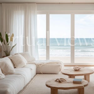 May include: A white sectional sofa with white throw pillows sits in a living room with large windows overlooking a beach. Two wooden coffee tables with a book and seashells on top are in front of the sofa.