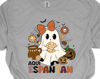 Könnte beinhalten: Graues T-Shirt mit einem Cartoon-Geist, der einen Keks und eine Tasse heiße Schokolade hält. Der Geist trägt eine rote Schleife. Der Text "Aqui Espantan" ist unter dem Geist gedruckt.