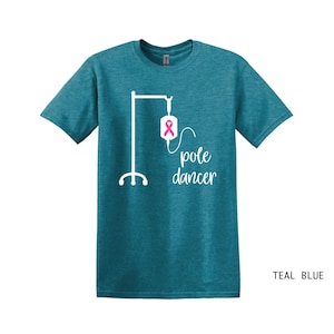 May include: Teal blue t-shirt with a white graphic of an IV pole with a pink ribbon on the bag and the text "pole dancer".