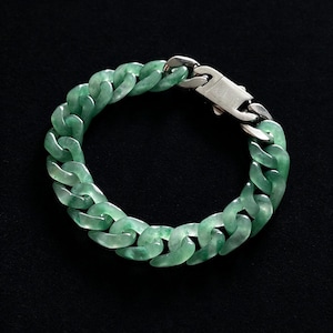 May include: A chain link bracelet featuring translucent, mottled green stone links with a polished silver-tone metal clasp. The bracelet is circular in shape, showcasing a smooth, glossy finish on each individual link and a secure locking mechanism.