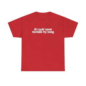 May include: A bright red short-sleeved t-shirt featuring the white text "AI could never recreate my swag" printed in a clean, sans-serif font across the centre of the chest. The garment has a classic crew neckline and a standard straight hem.
