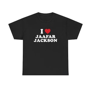 May include: A black short-sleeve t-shirt featuring the white text I, a red heart symbol, and the white text JAAFAR JACKSON printed on the center of the chest. The garment has a crew neckline and a standard fit with short sleeves and a straight hem.