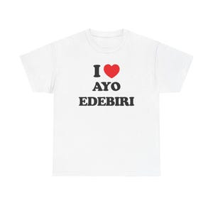 May include: White t-shirt with the text "I ❤️ Ayo Edebiri" in black and red. The heart symbol is red. The shirt is a classic crew neck style.