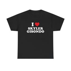 Könnte beinhalten: Ein schwarzes T-Shirt mit kurzen Ärmeln, das auf der Brust den weißen Text I, ein rotes Herzsymbol und den weißen Text SKYLER GISONDO zeigt. Das Kleidungsstück hat einen Rundhalsausschnitt und eine Standardpassform mit einem Grafikdruck.