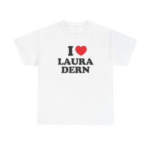 May include: White t-shirt with the text "I ❤️ LAURA DERN" in black letters and a red heart symbol. The shirt is a crew neck style and appears to be made of a soft material.