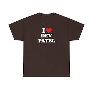 Könnte beinhalten: Ein braunes T-Shirt mit dem Text "I ❤️ DEV PATEL" in Weiß und einem roten Herzsymbol. Das T-Shirt hat einen Rundhalsausschnitt.