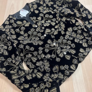 May include: A black velvet jacket with a gold floral pattern. The jacket has a button closure and long sleeves.
