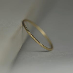 May include: A thin gold band ring with a hammered texture.