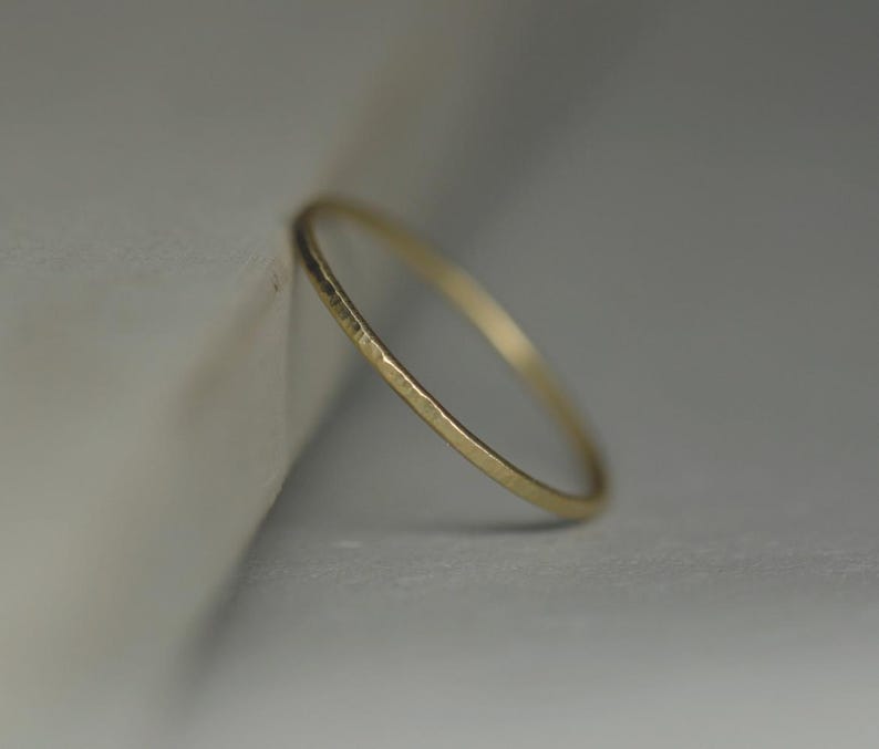 May include: A thin gold band ring with a hammered texture.
