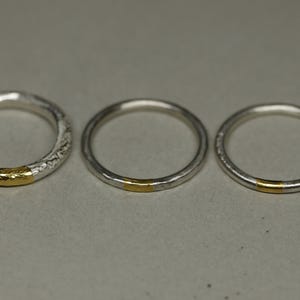 May include: Three silver rings with a thin gold band around each ring.