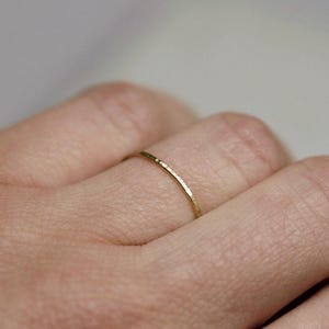 May include: A thin gold band ring with a hammered texture.