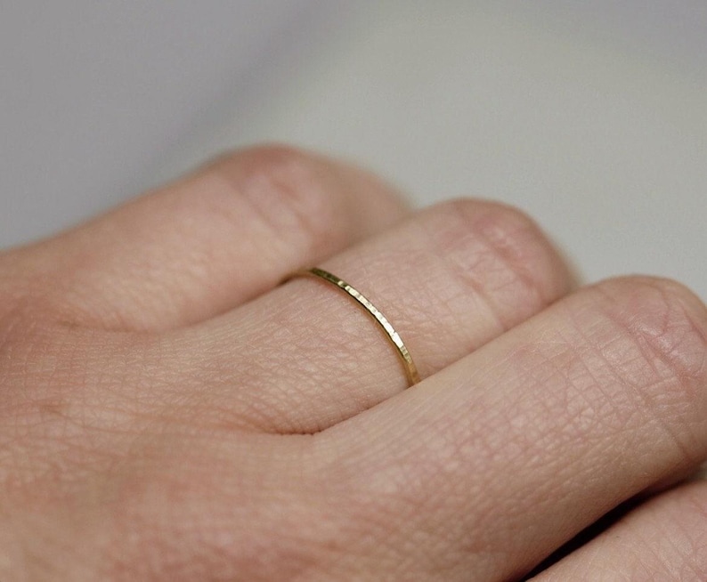 May include: A thin gold band ring with a hammered texture.